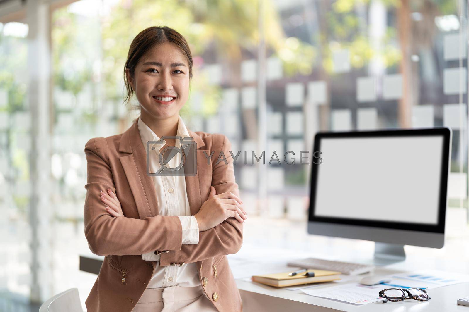 Royalty free image of portrait of young asian business woman standing arms crossed in modern office. by nateemee
