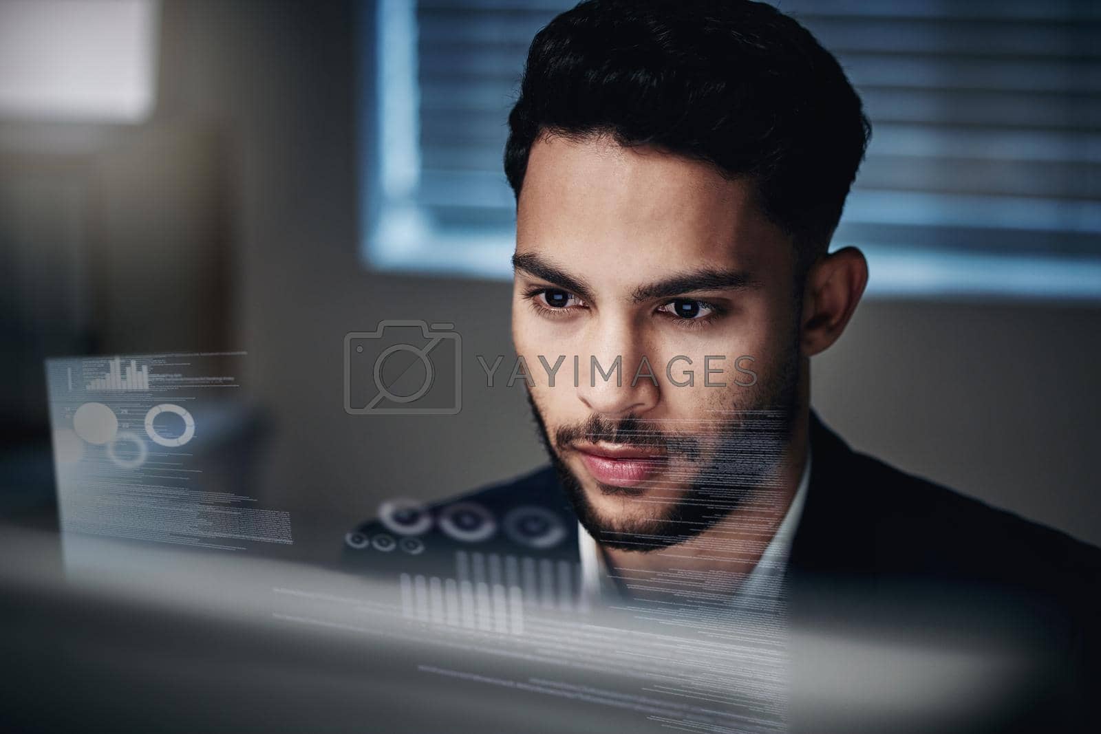 Royalty free image of Data is my second language. Shot of a handsome young businessman sitting alone in the office at night and using his computer. by YuriArcurs