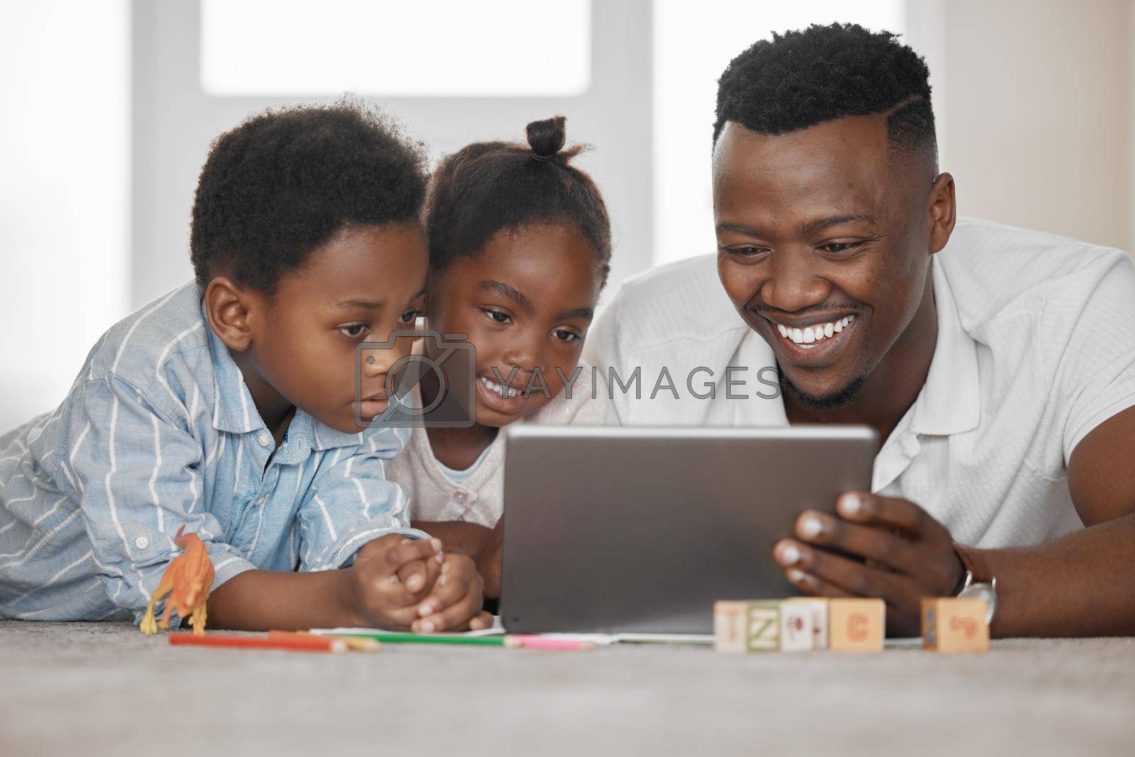 Shot of a father using a digital tablet with his son and daughter at home.