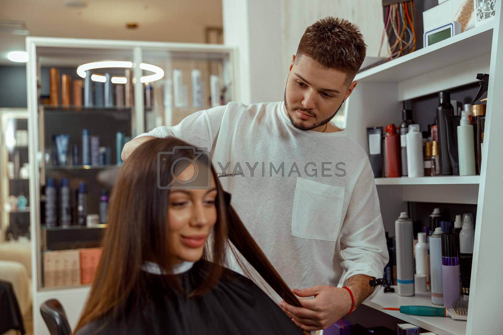 Professional male hairdresser cutting hair of woman at beauty salon. Haircut, hair care