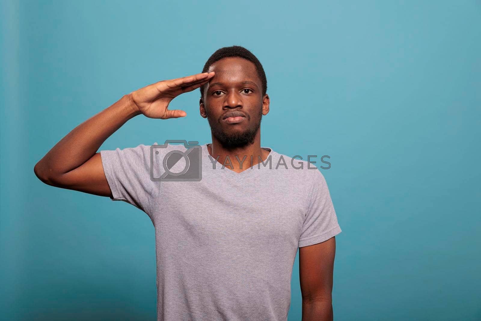 Royalty free image of Young man doing military salute with hand over forehead by DCStudio