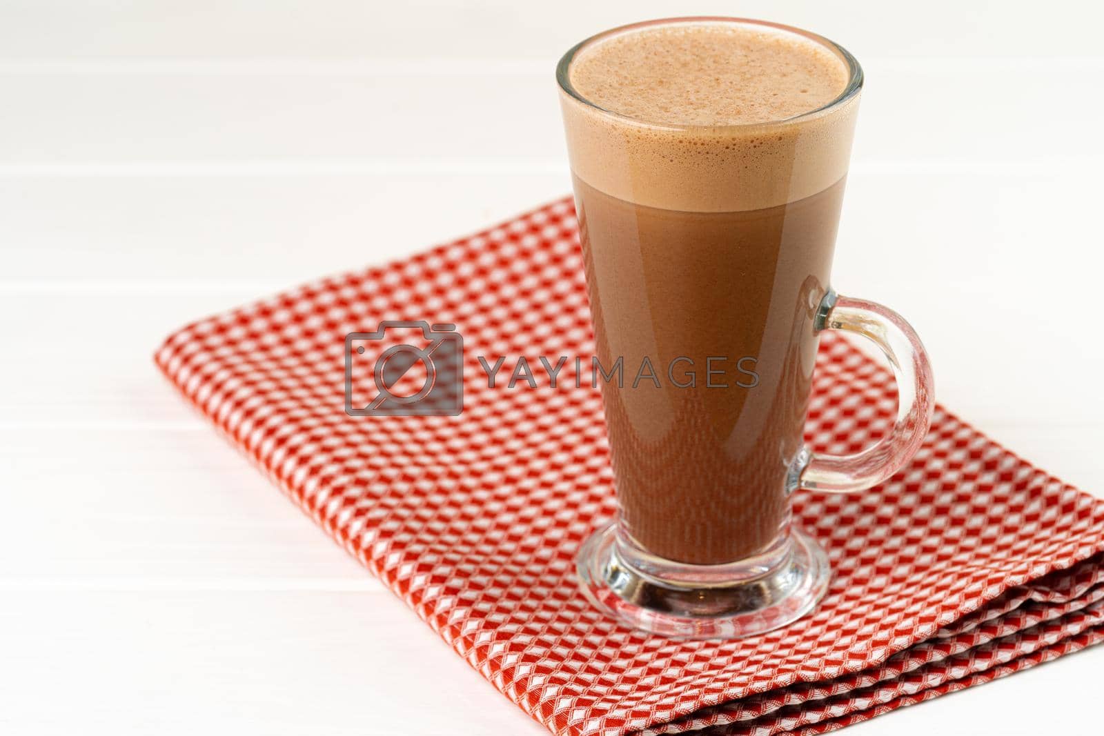 Glass cup of cocoa drink on white wooden table close up