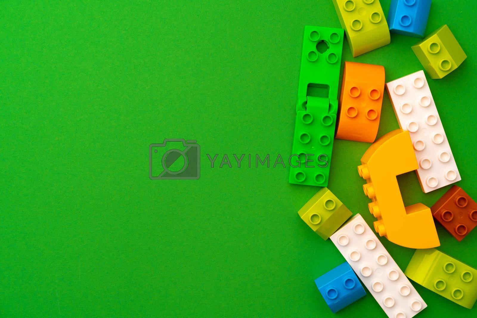 Royalty free image of Details of kids plastic constructor on green background by Fabrikasimf