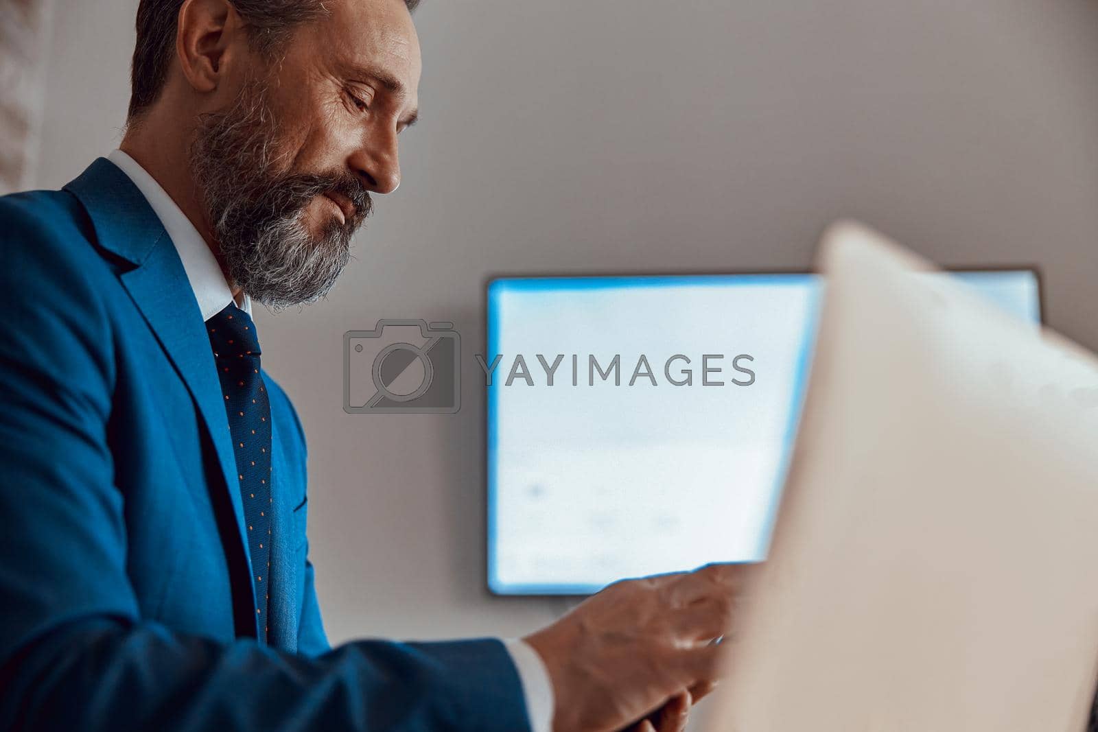 Royalty free image of Adult businessman working at with laptop on desk by Yaroslav_astakhov