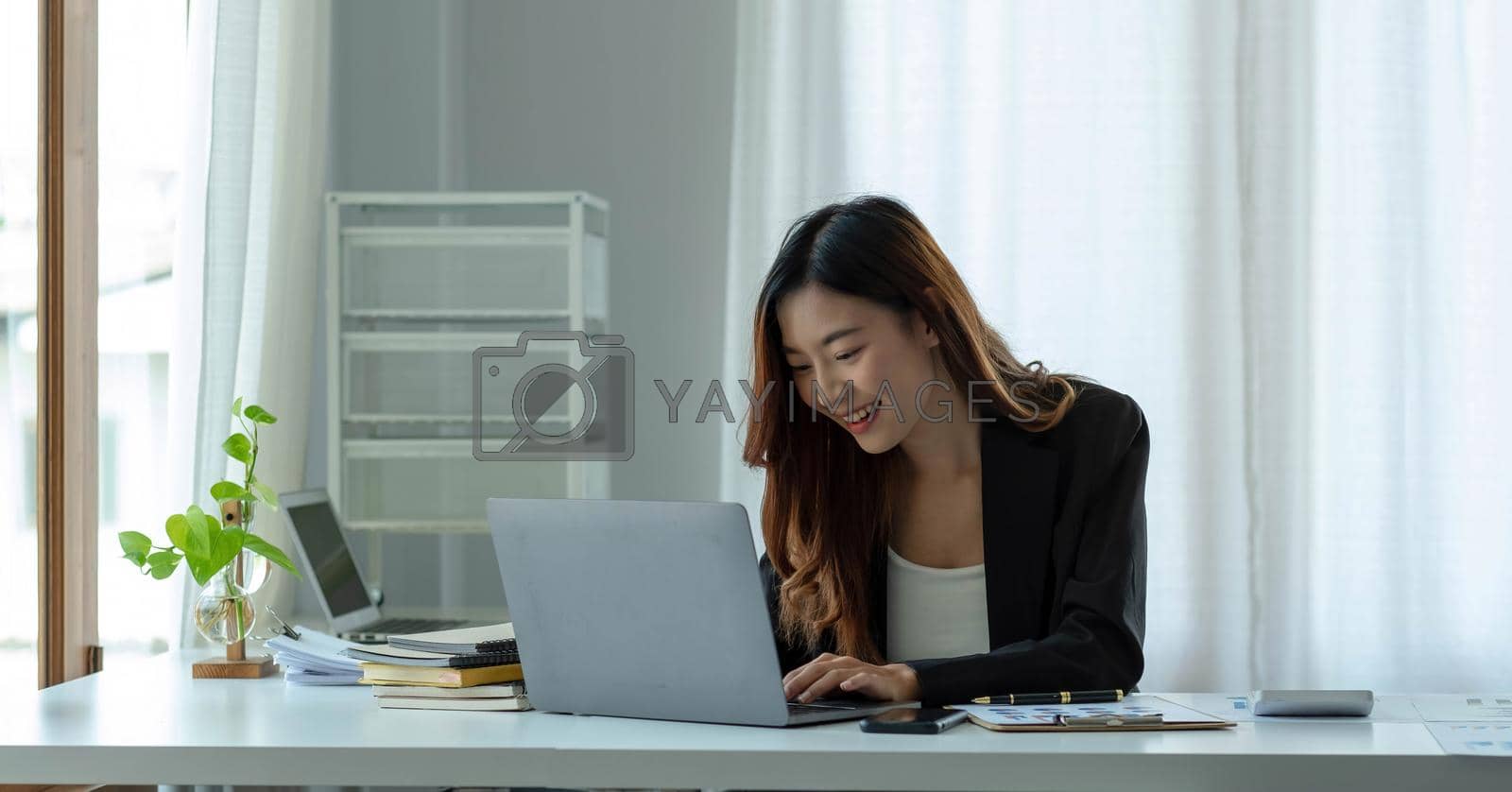 Royalty free image of Charming asian businesswoman sitting working on laptop in office. by wichayada