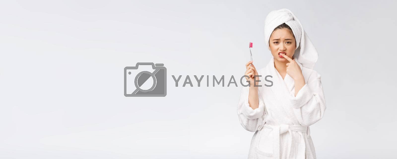 Royalty free image of Unhappy beautiful woman brushing her teeth on white background by Benzoix