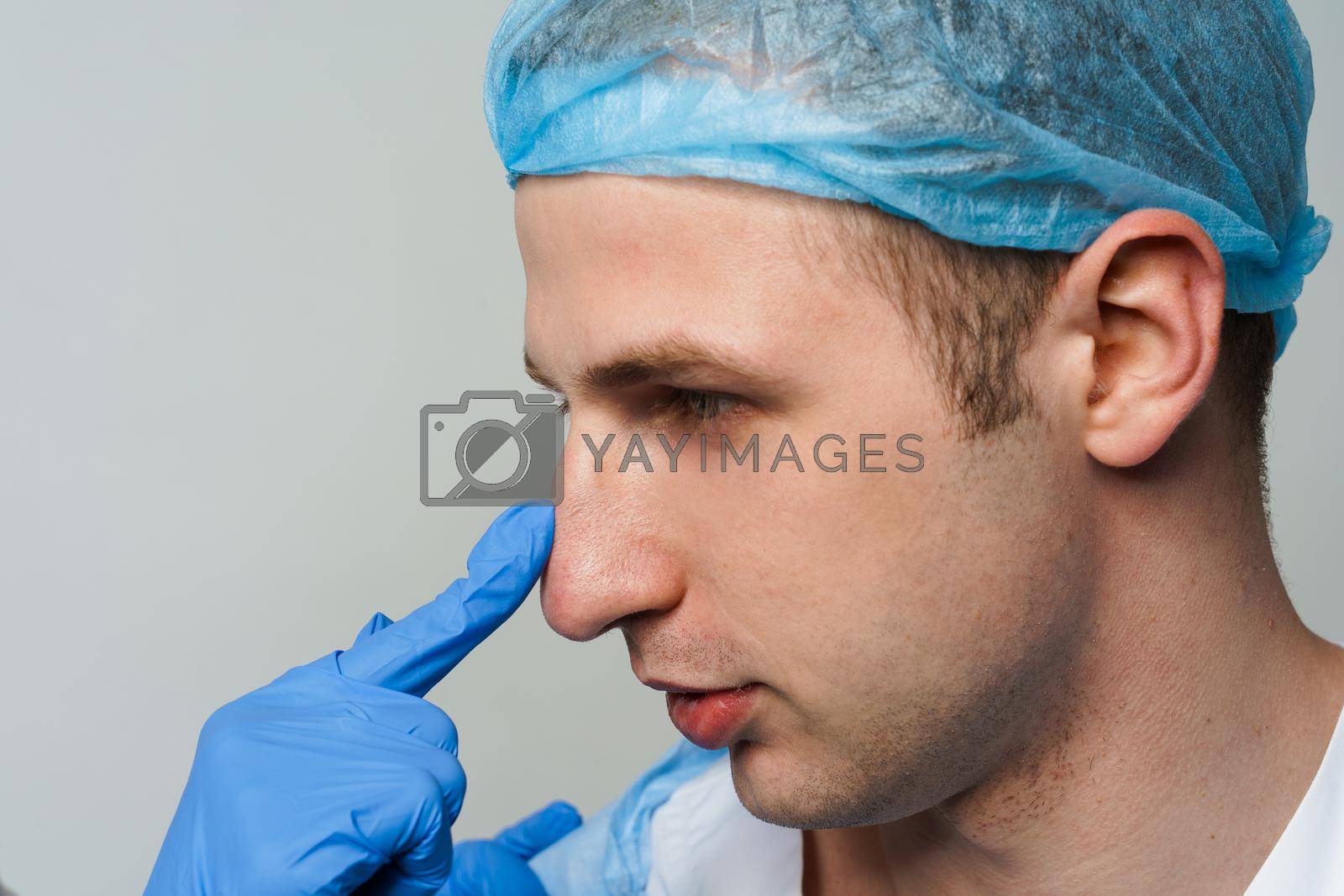 Royalty free image of Facebuilding. Septoplasty and nose rhinoplasty. Doctor touches man nose on consultation. Inspection before plastic surgery. Cosmetic rejuvenating facial treatment by Rabizo