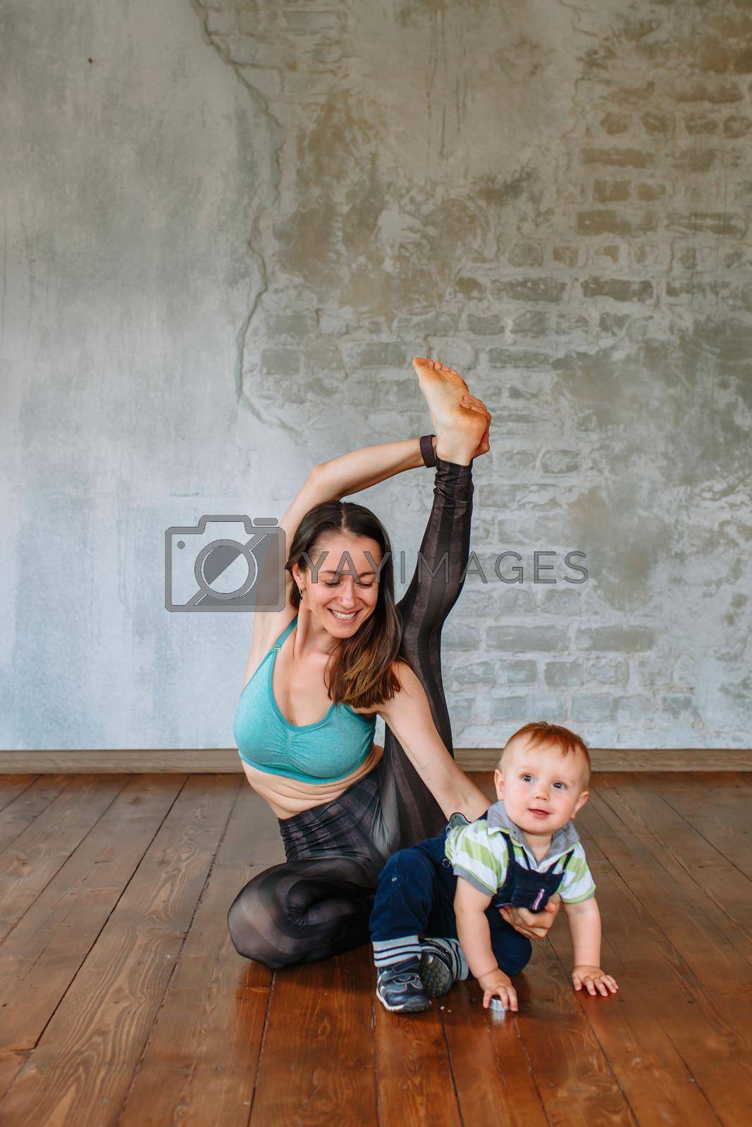 Yoga girl performs an exercise, next to her little son