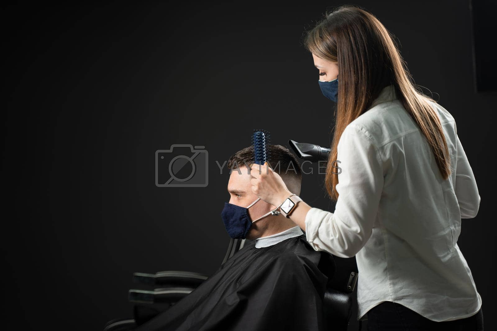 Royalty free image of Barbershop service at coronavirus covid-19 period. Drying hair after cutting in barbershop for handsome man. Using mask. by Rabizo