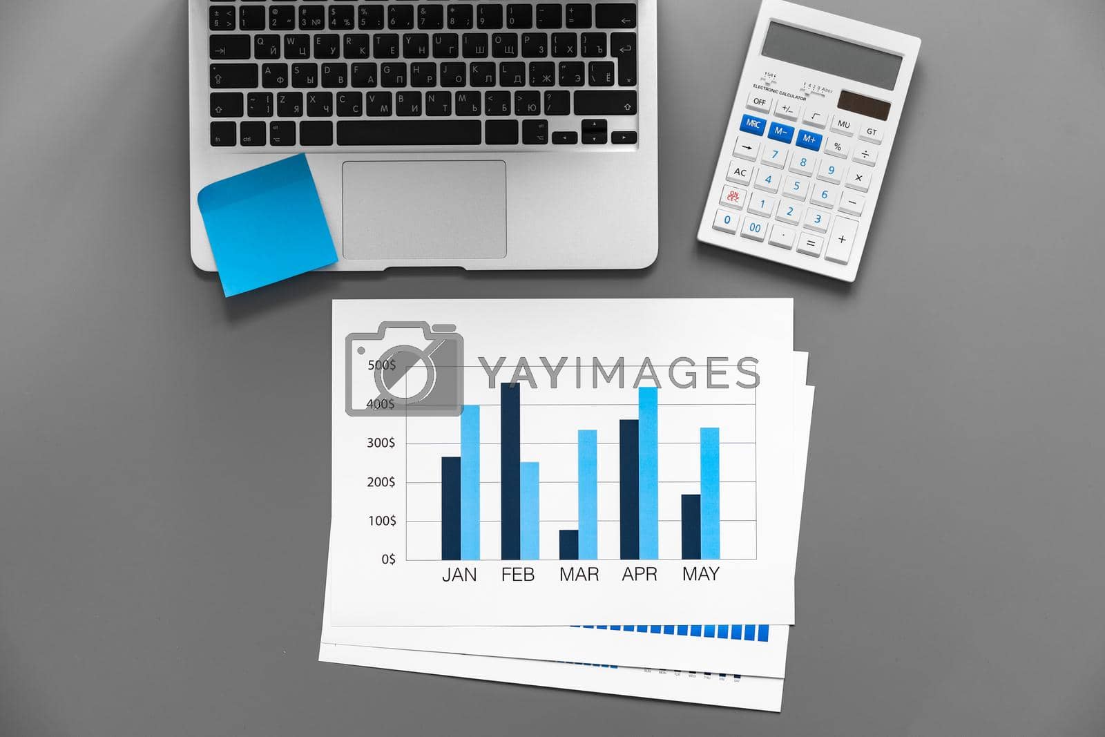 Royalty free image of Printed graphs and laptop on dark gray surface by Fabrikasimf