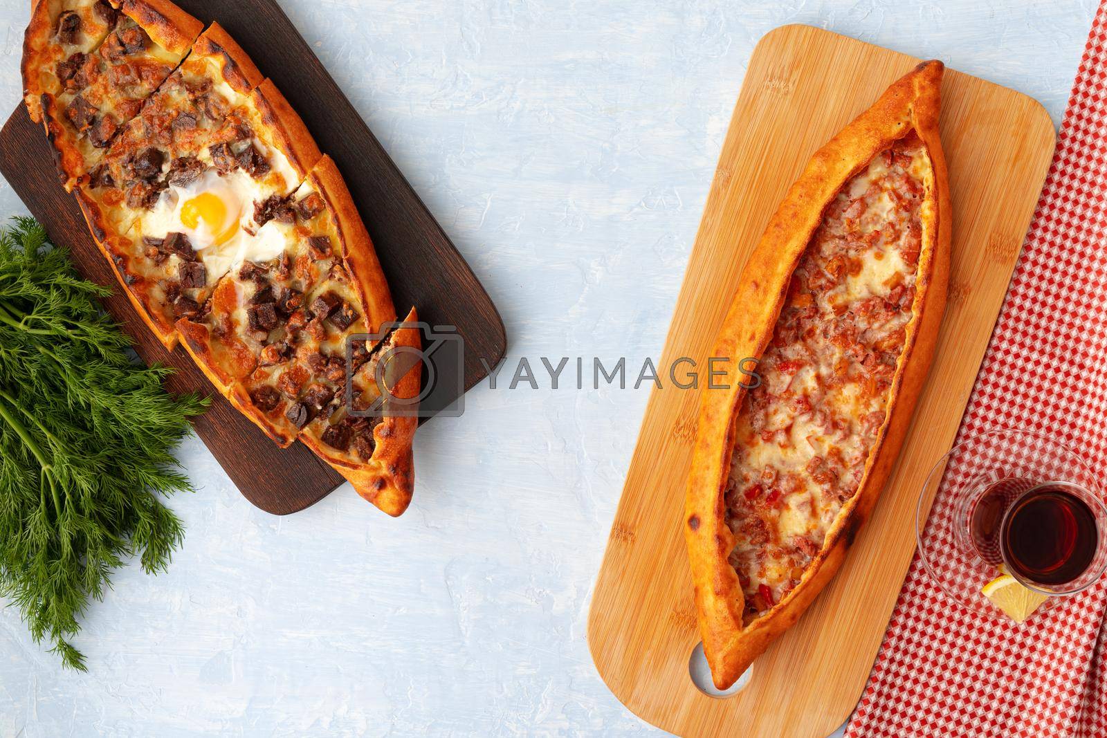 Royalty free image of Turkish baked Pide bread on light blue wooden surface by Fabrikasimf