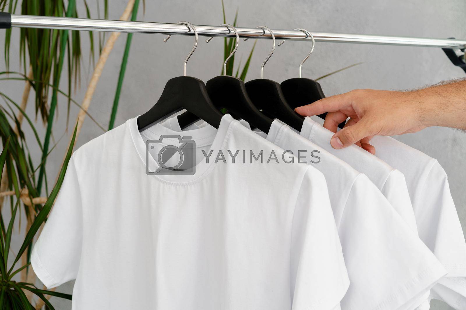Royalty free image of Male hand holds hanger with blank white t-shirt by Fabrikasimf