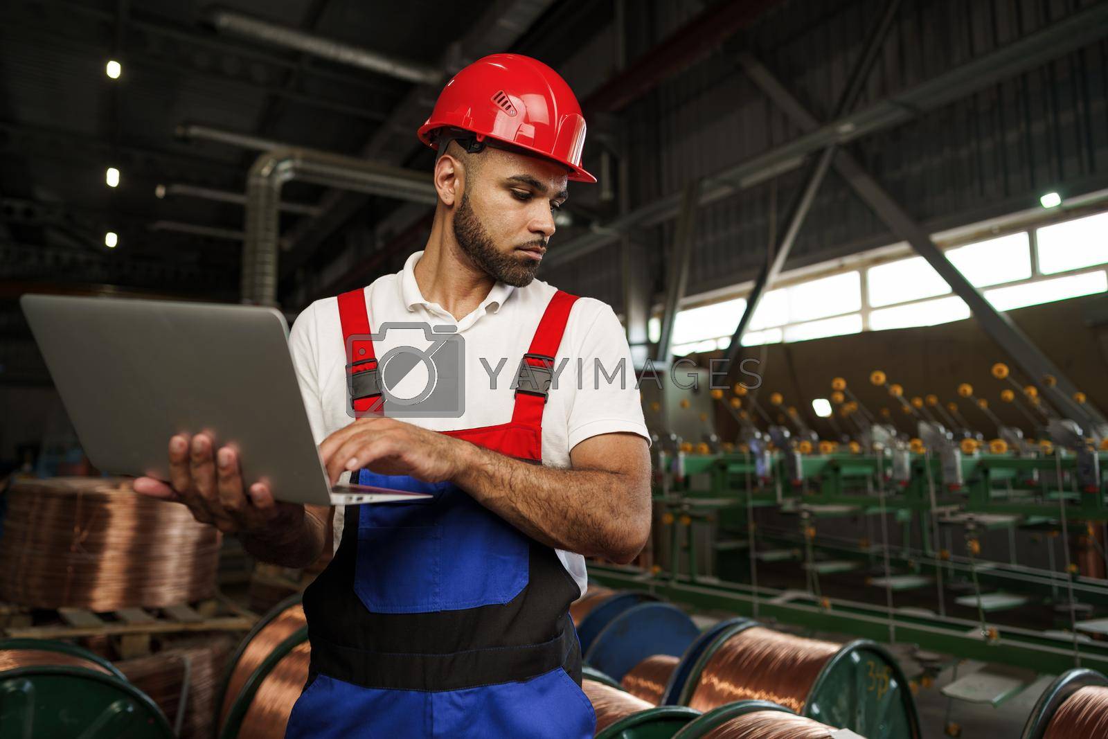 Royalty free image of Industrial worker with laptop working in a cable production plant by Fabrikasimf