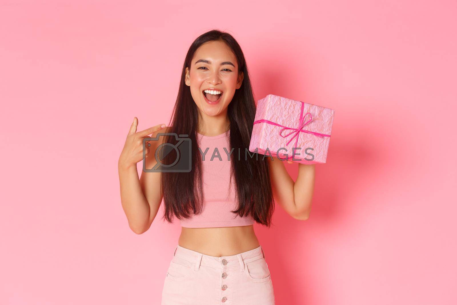 Holidays, celebration and lifestyle concept. Beautiful happy asian girl pointing at herself, its her birthday, receive gift wrapped in pink paper, smiling broadly over studio background.