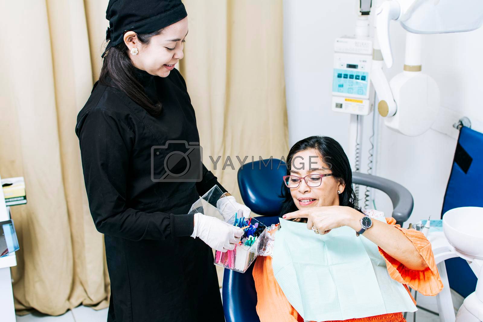 Patient with dentist choosing dental braces, Dentist with patient choosing metal braces, Patient with dentist choosing rubber band