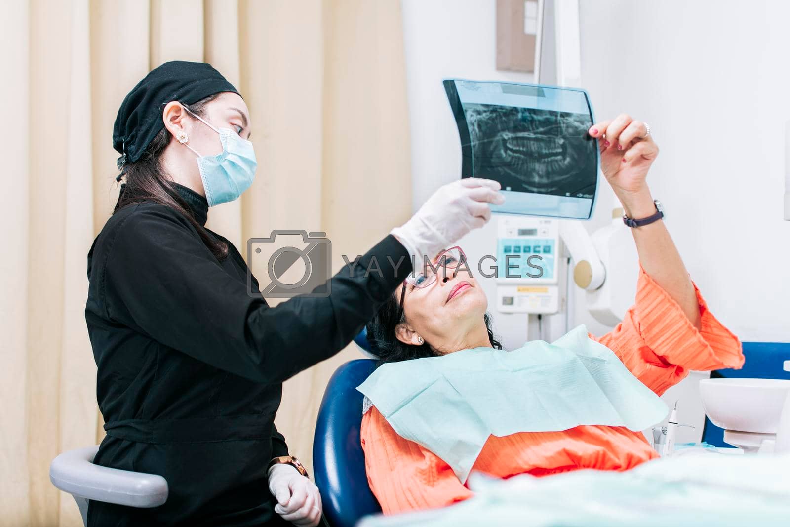 Dentist showing x-ray to patient, patient looking at x-ray with dentist, dental patient holding her x-ray, a dentist with x-ray examination