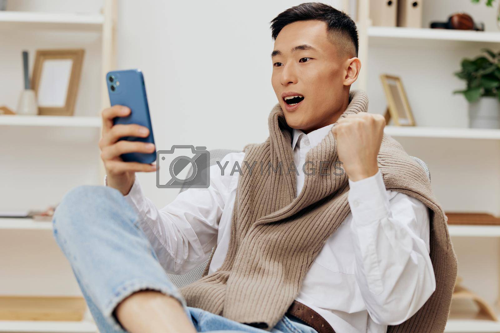 teenager communication with the phone in his hands sits on a chair interior Lifestyle work. High quality photo