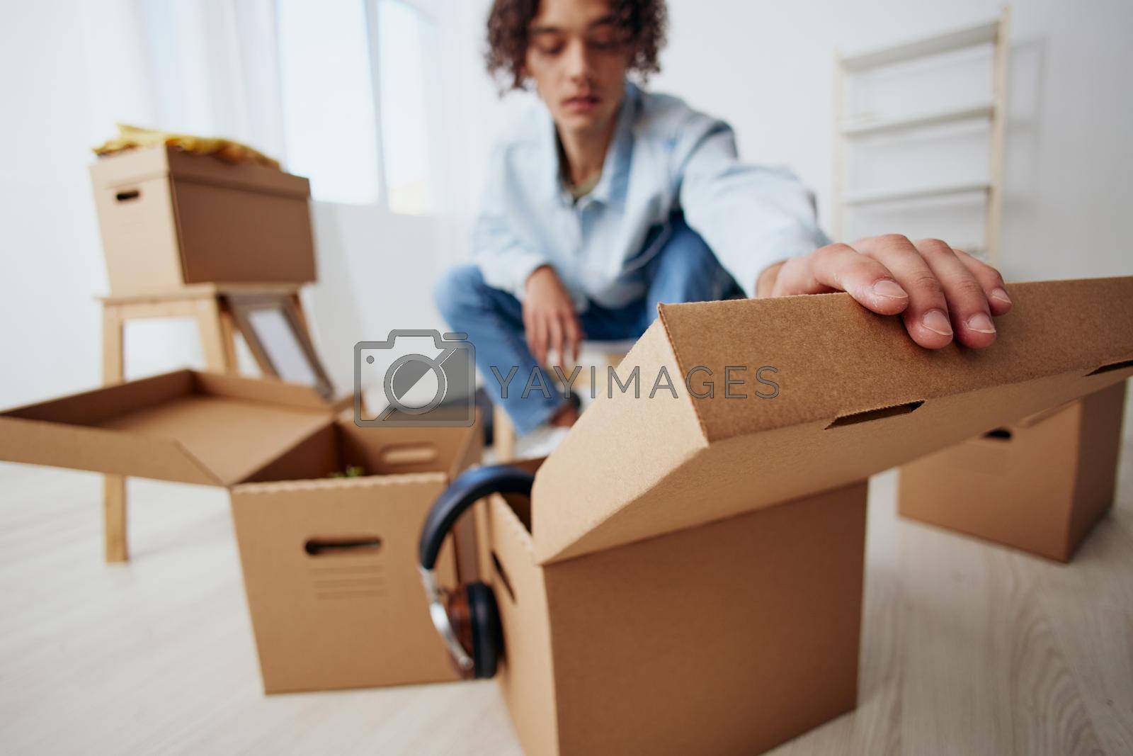 Royalty free image of guy with curly hair sitting on a chair with boxes moving interior by SHOTPRIME