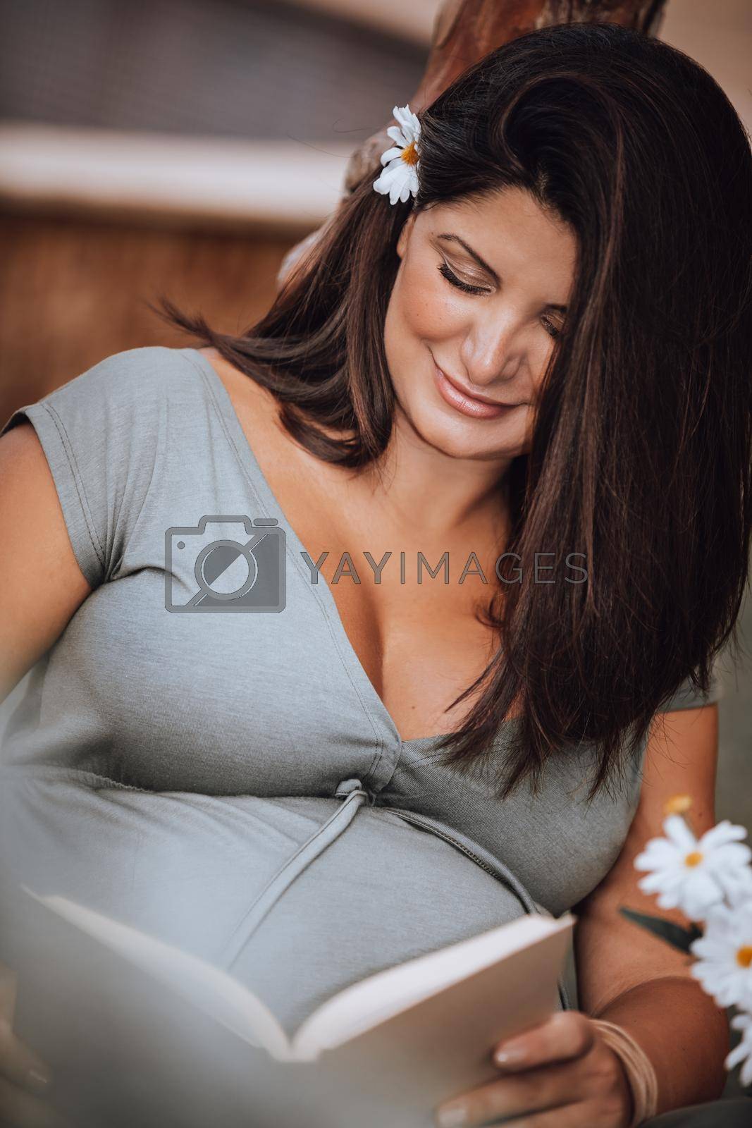 Portrait of a Cute Brunette Pregnant Woman with Pleasure Reading Book. Reads Fairy Tale for Future Baby. Enjoying Pregnancy.