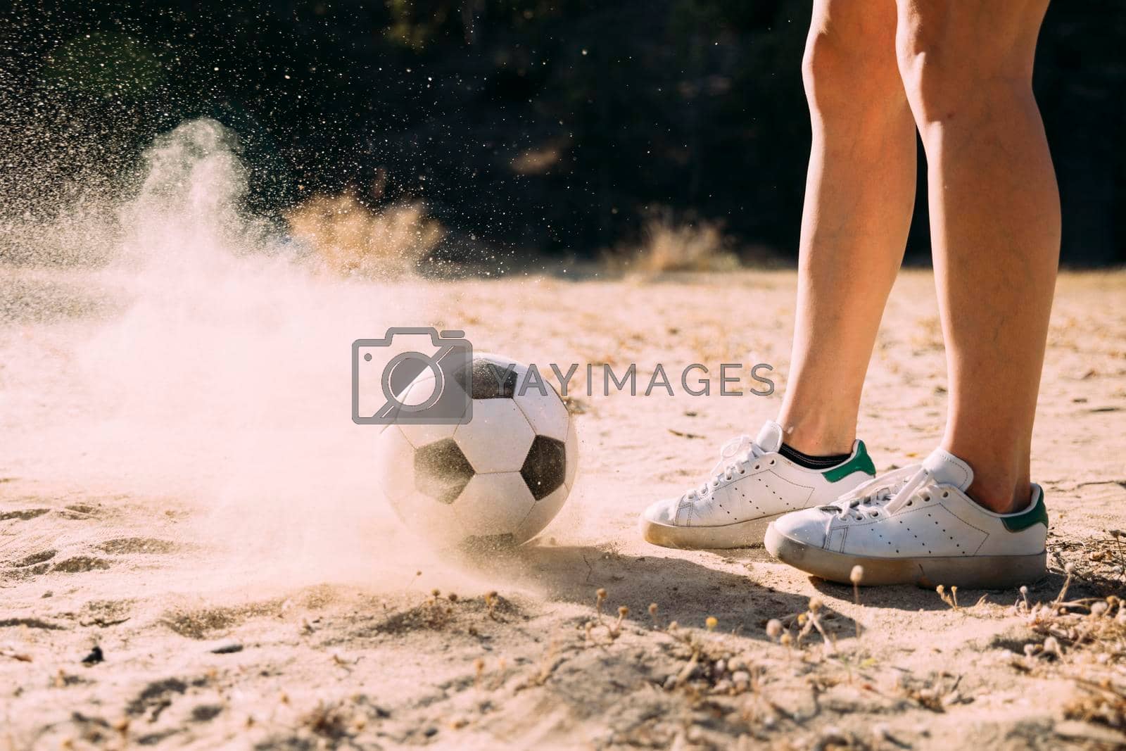 Royalty free image of crop athletic legs standing by football outdoors by Zahard