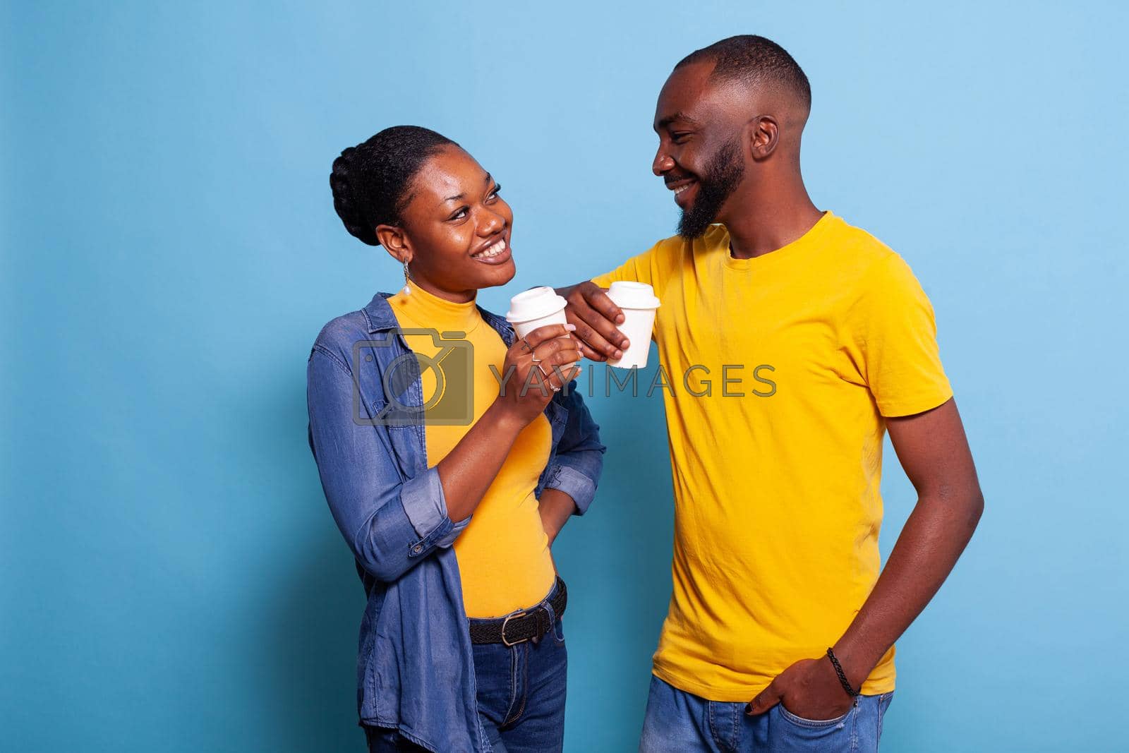 Cheerful couple holding cup of coffee and enjoying romance in front of camera. People in relationship laughing and looking at each other. Boyfriend and girlfriend showing affection.