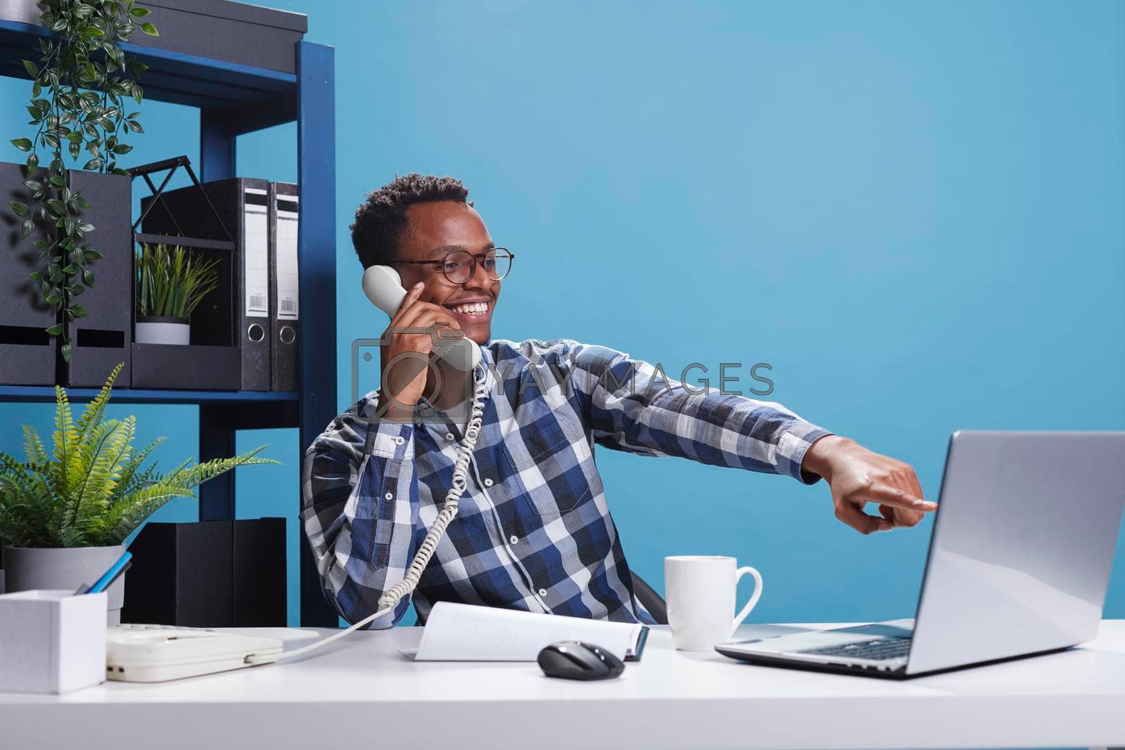 Royalty free image of Marketing company happy joyful african american office worker on landline call with accountant by DCStudio