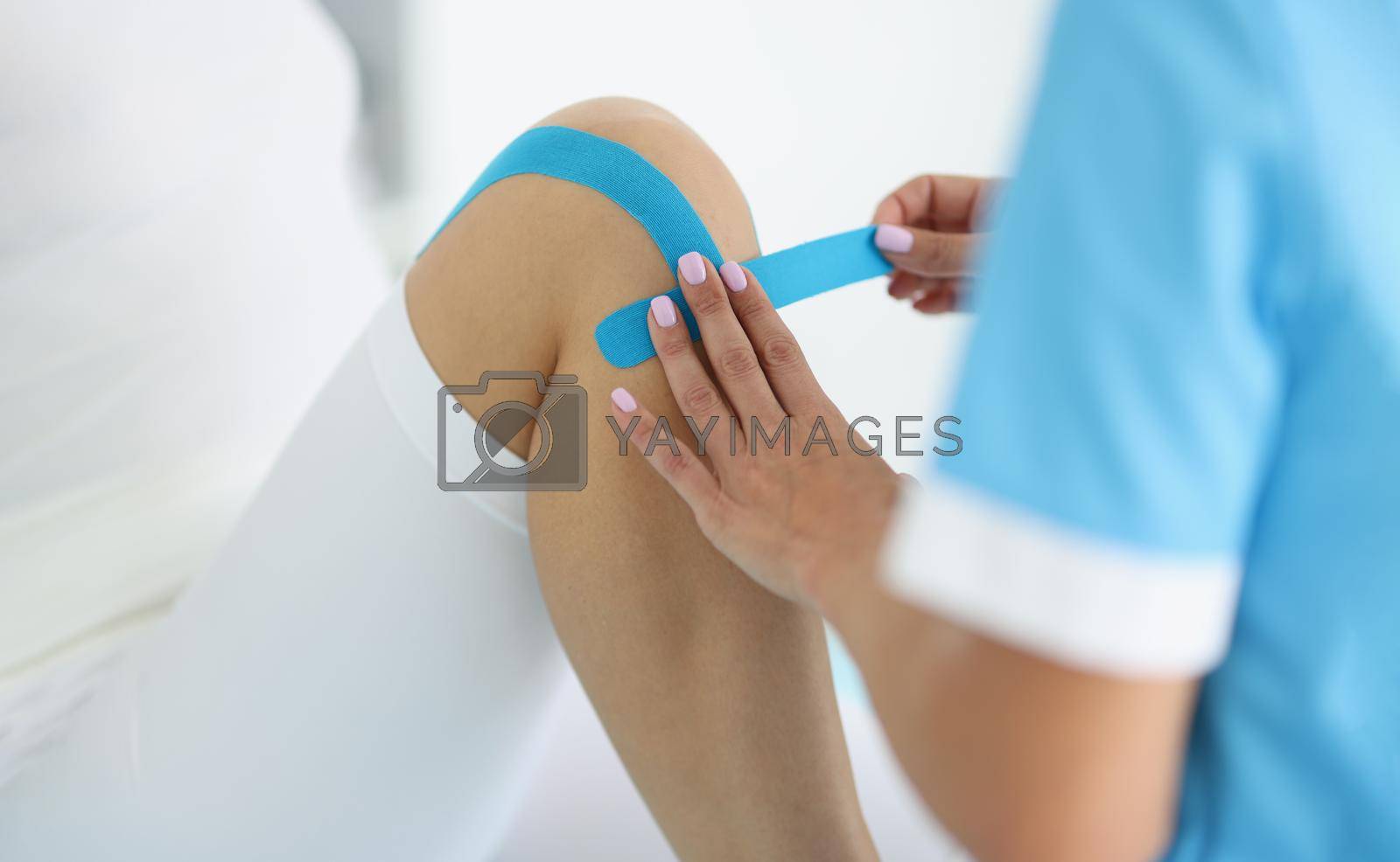 Royalty free image of Physiotherapist put kinesiology tape on clients knee, remove pain, rehabilitation center by kuprevich