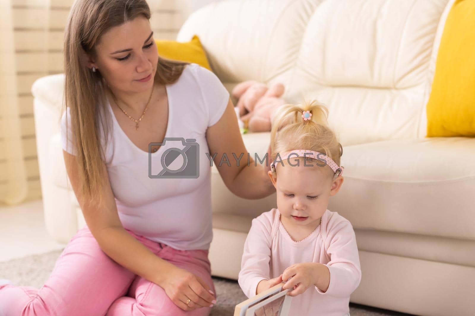 Royalty free image of Child girl with cochlear implant with her mother at home. Hear impairment and deaf community concept by Satura86