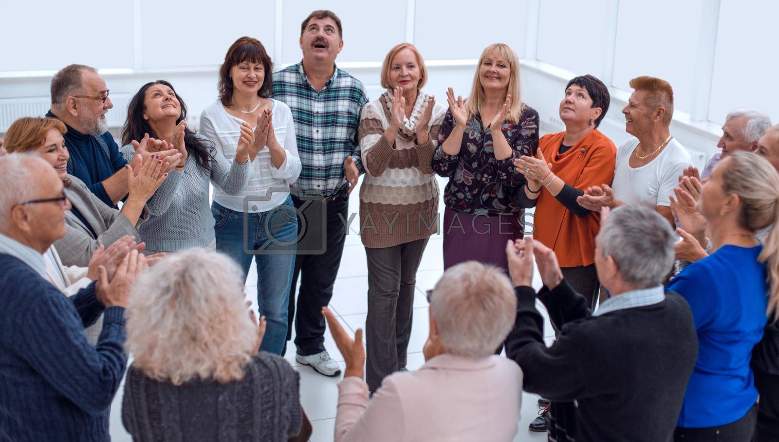 group of happy elderly people clap hands