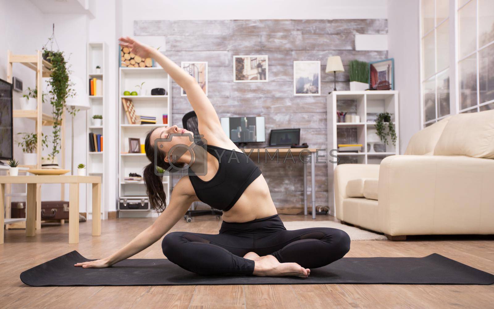 Adult woman in fitness leggings doing yoga on mat in home. Lotus yoga position.