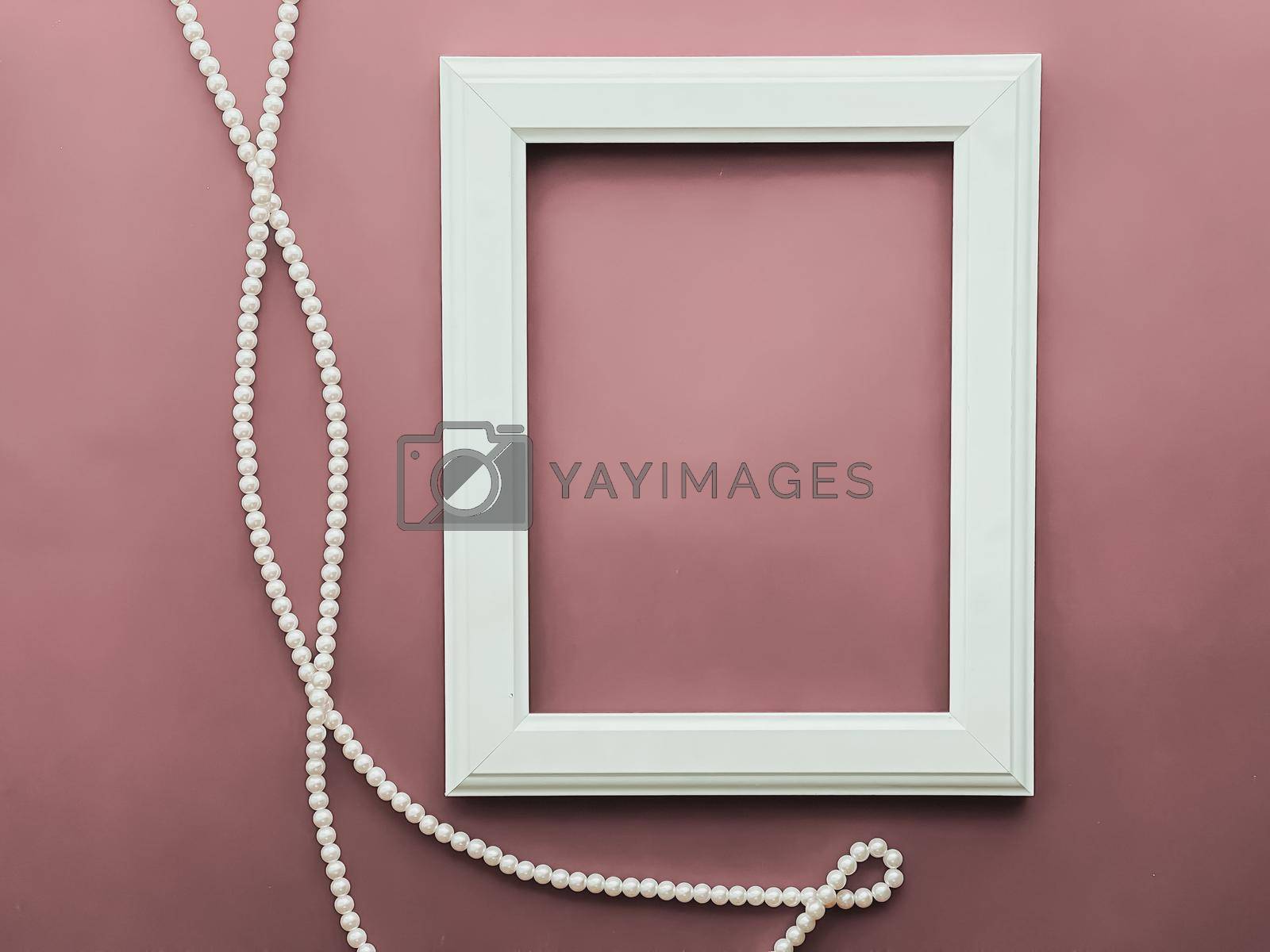 Royalty free image of Vertical frame and pearl jewellery on blush pink background as flatlay design, artwork print or photo album by Anneleven