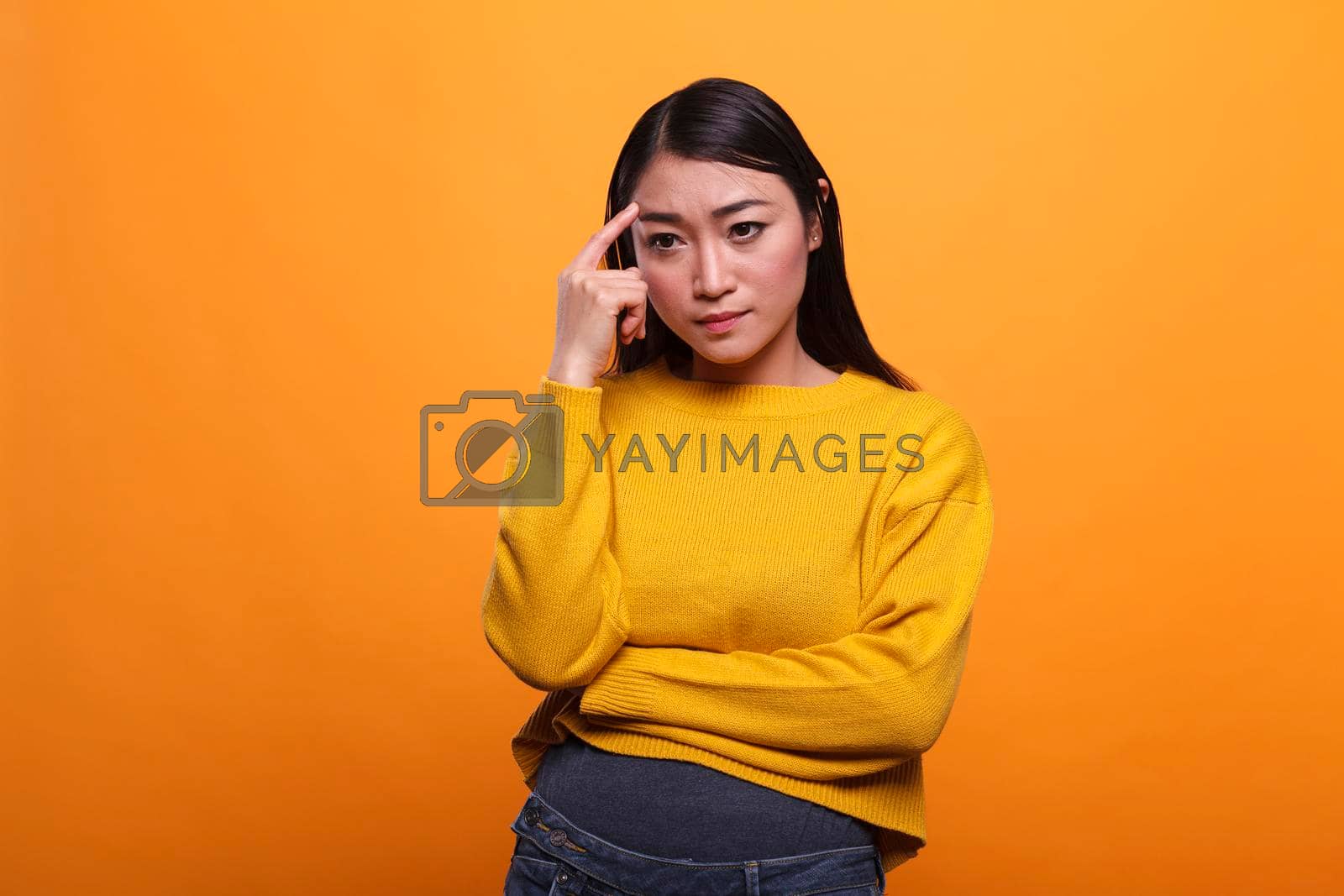 Royalty free image of Serious pensive woman focused on introspection thoughts in a contemplation state on orange background. by DCStudio