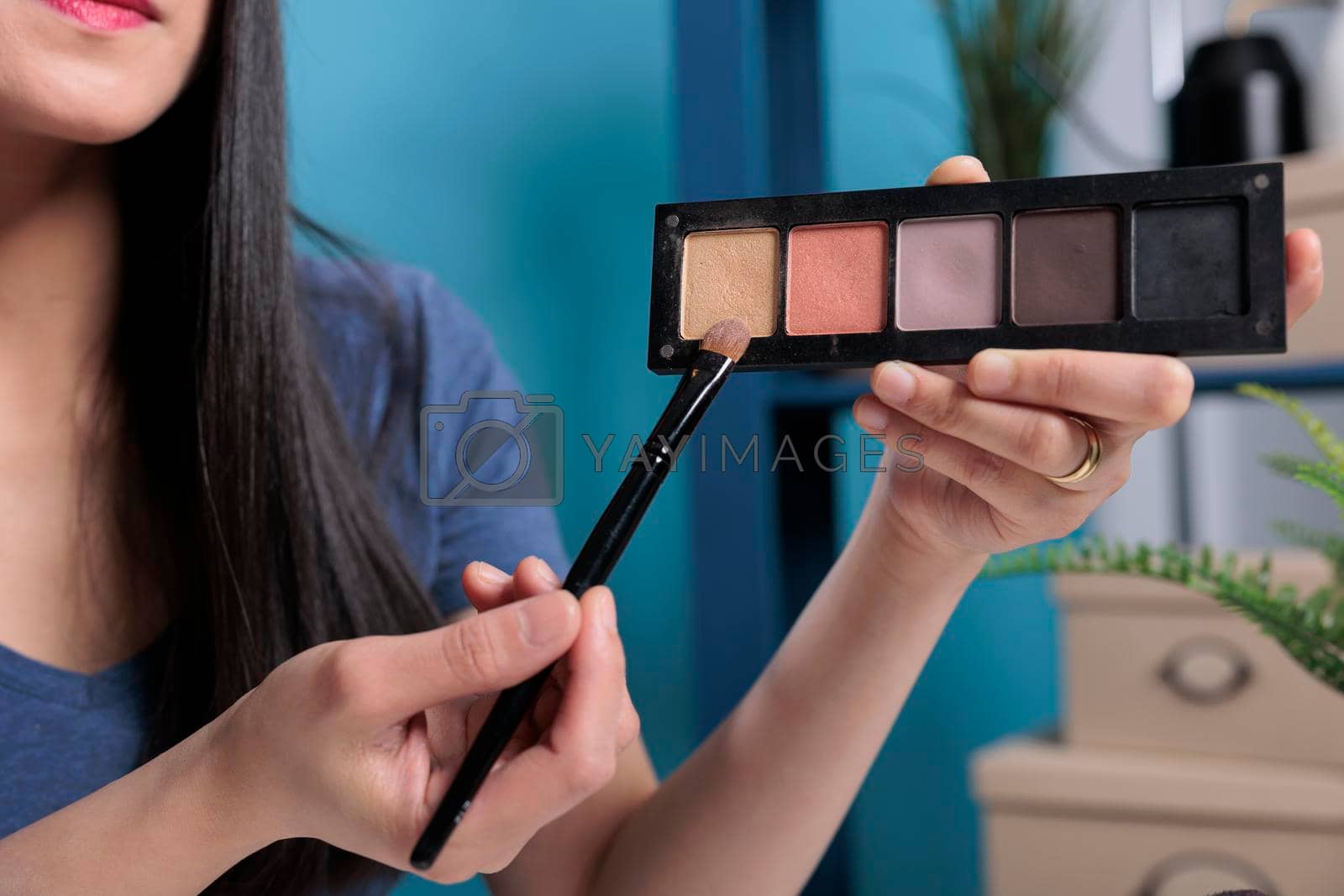 Beauty guru holding cosmetic palette showing at camera while filming make up tutorial reviewing product for vlogging channel in studio. Social media influencer recording cosmetology podcast. Close up