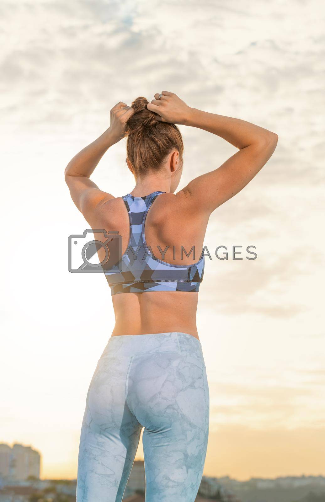 Royalty free image of Sporty woman with slim tanned body in sportswear posing on sky background. by MikeOrlov