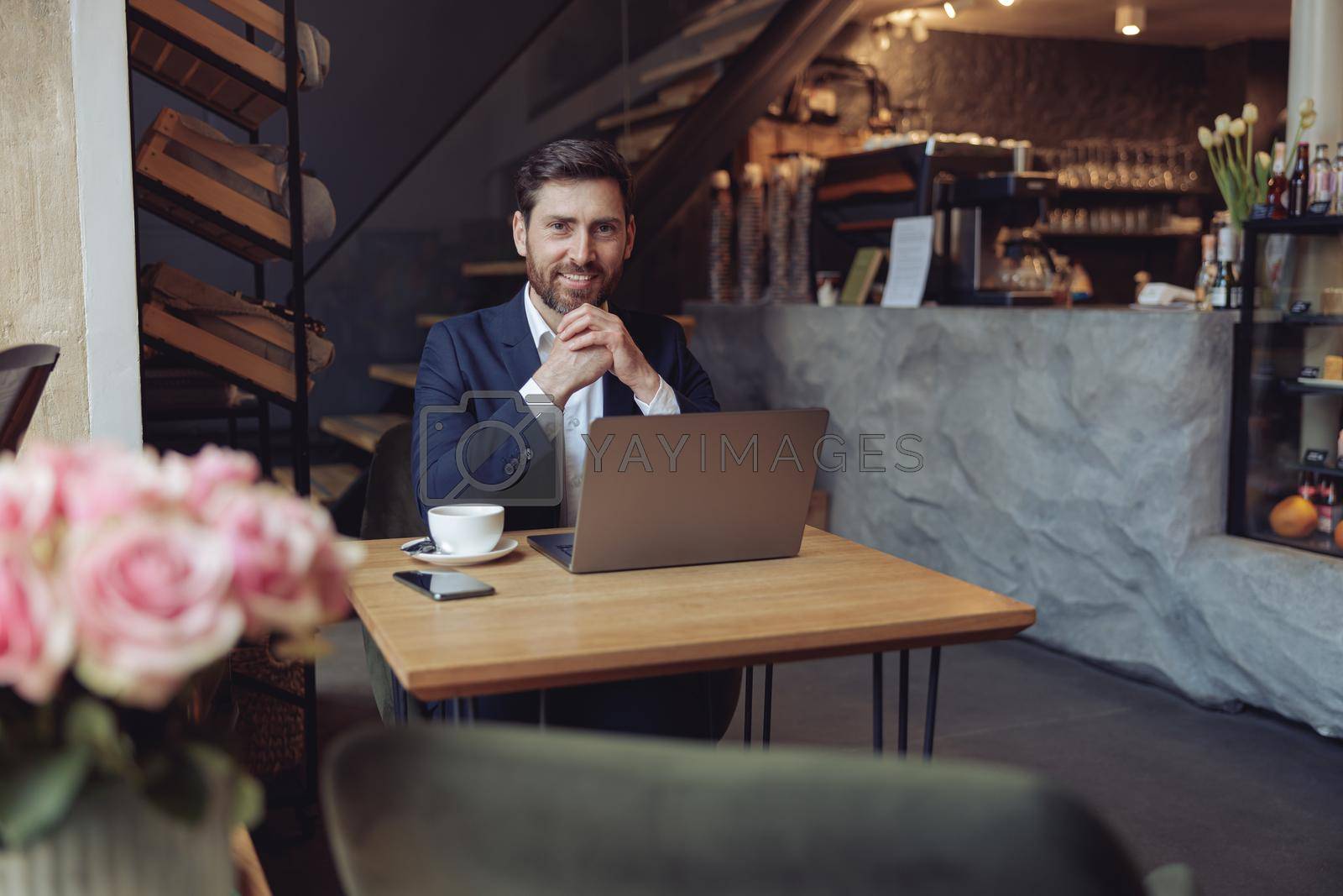 Royalty free image of Attractive elegant successful man with coffee at laptop in luxury cafe smiling with chin on hands. by Yaroslav_astakhov