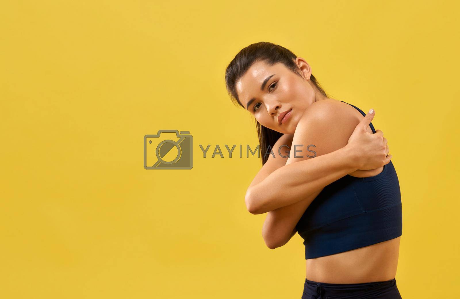 Royalty free image of Pretty woman hugging herself while looking at camera in studio. by SerhiiBobyk