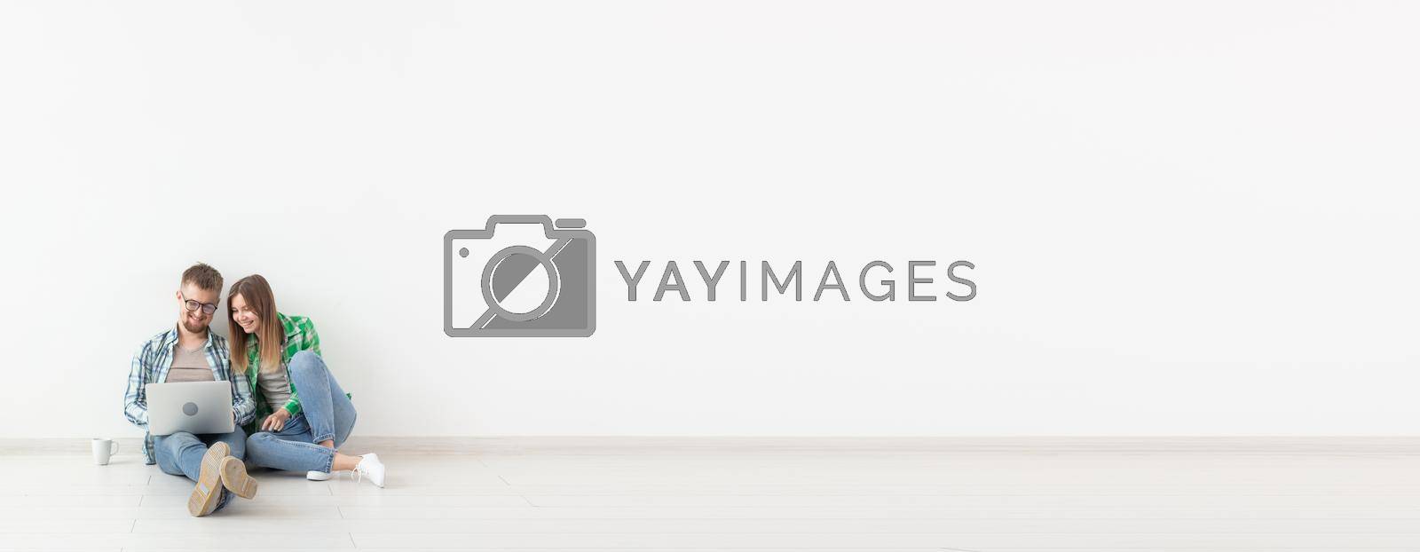 Royalty free image of Planning summer vacation or online order. Cute young couple searching hotel and resort online using laptop on floor at home - white background banner with copy space and place for advertising by Satura86