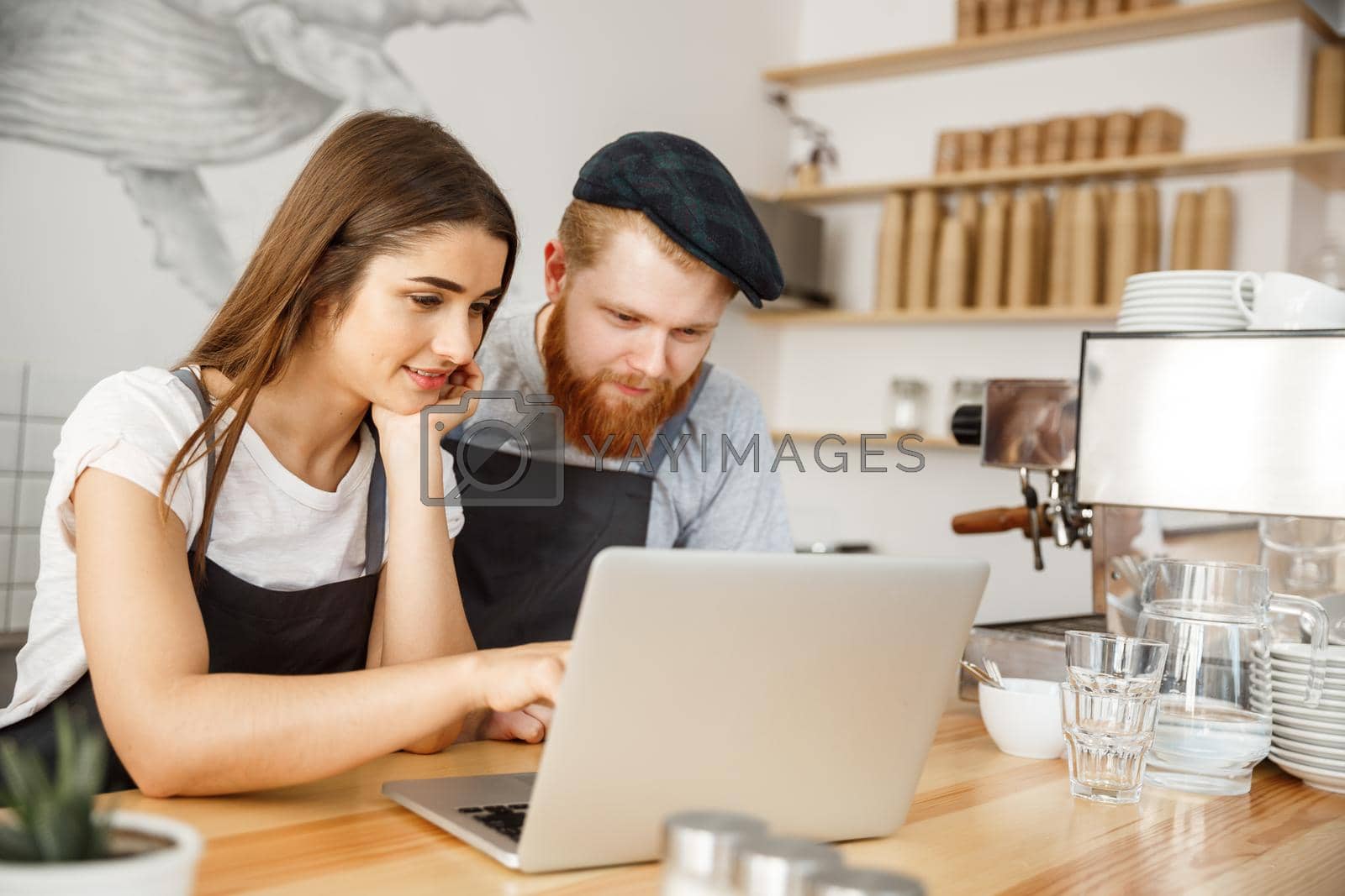 Royalty free image of Coffee Business Concept - Satisfied and smile owners look on laptop for online orders at coffee shop by Benzoix