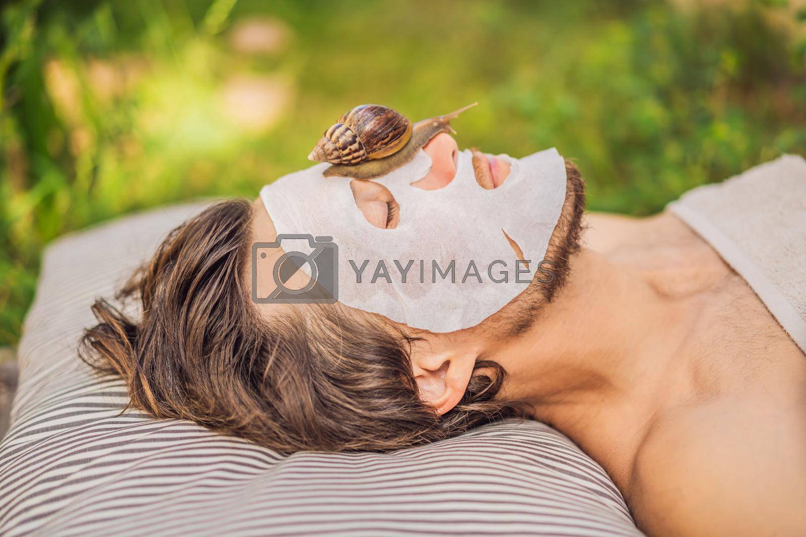 Young man makes a face mask with snail mucus. Snail crawling on a face mask. SPA for man, SPA for all.