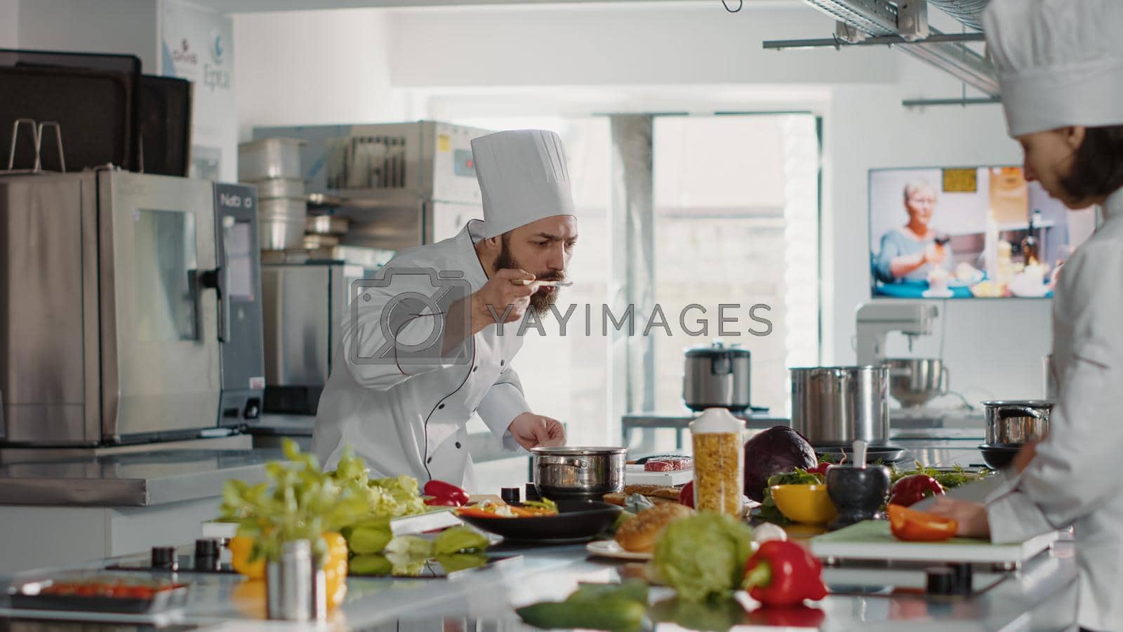 Royalty free image of Professional chef testing soup taste in pot on stove by DCStudio