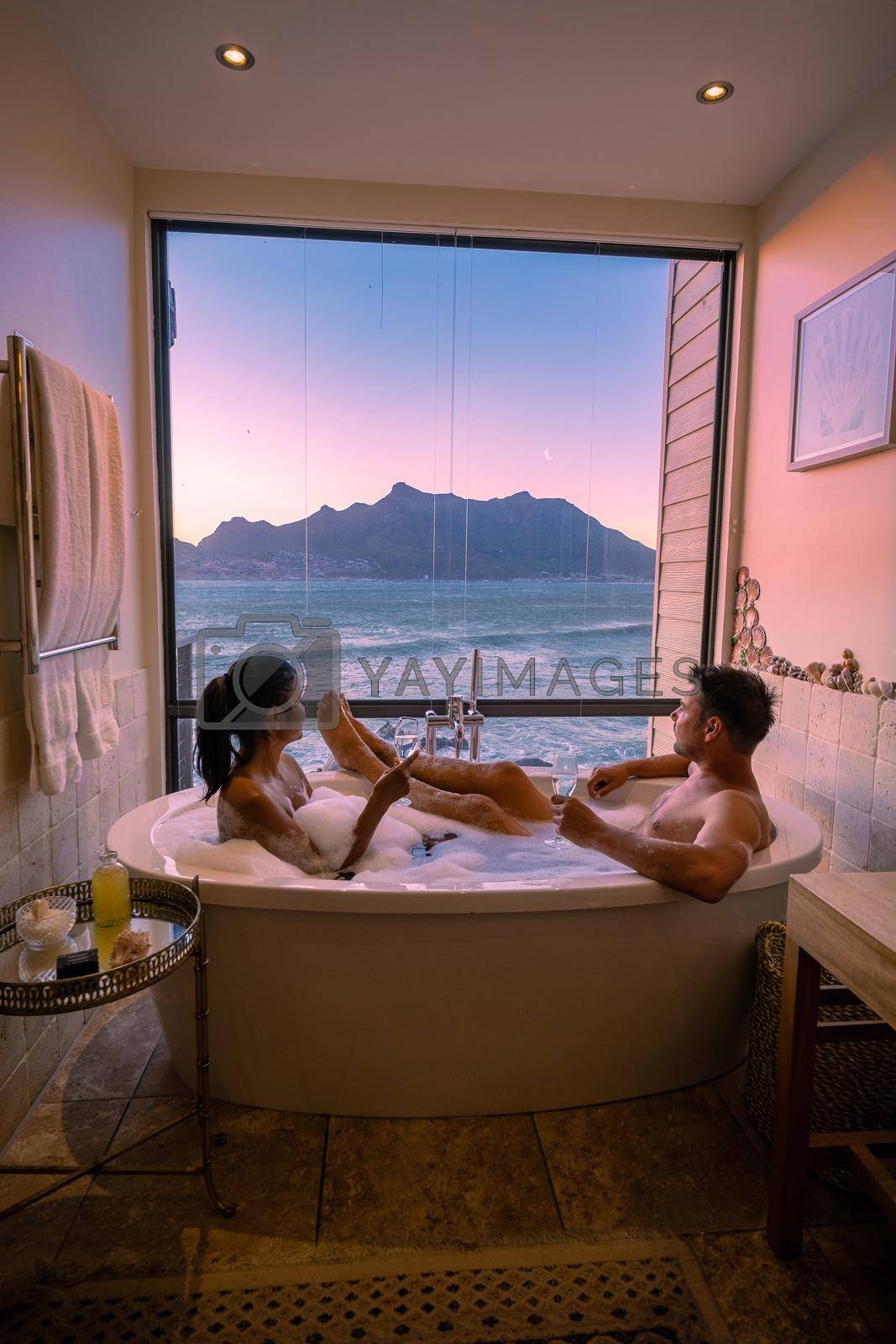 Royalty free image of man and woman in bath tub jaccuzi on vacation, couple man and woman in bath tub looking out over the ocean of Cape Town South Africa during vacation by fokkebok