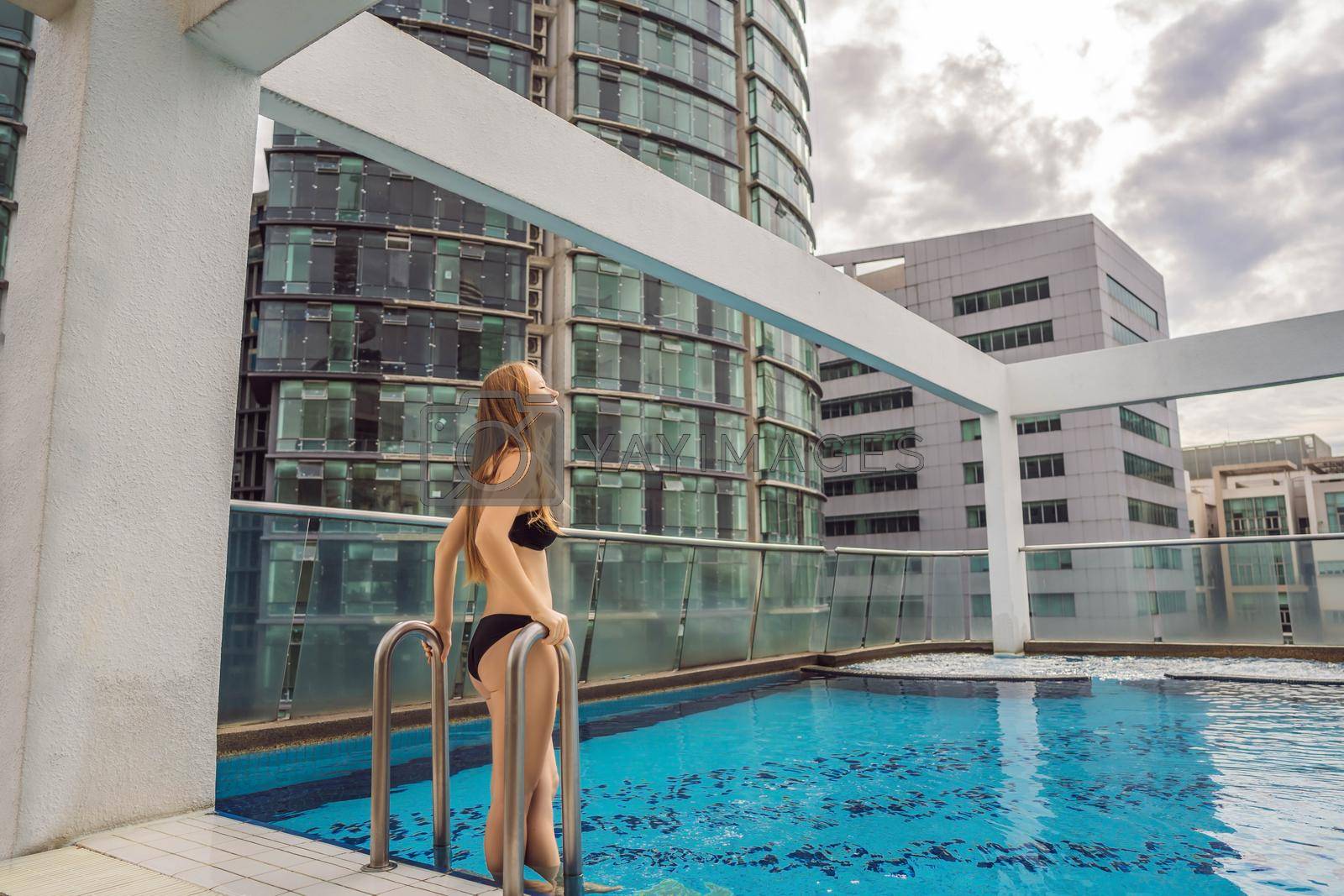 Malaysia, Kuala Lumpur November 21, 2018: Young woman in the pool among the skyscrapers and the big city. Relax in the big city. Rest from stress.