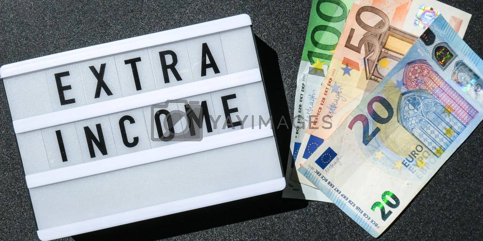 Royalty free image of Lightbox board with word EXTRA INCOME in black letters around euro banknotes. Money, Business, finance, investment, saving by anna_stasiia