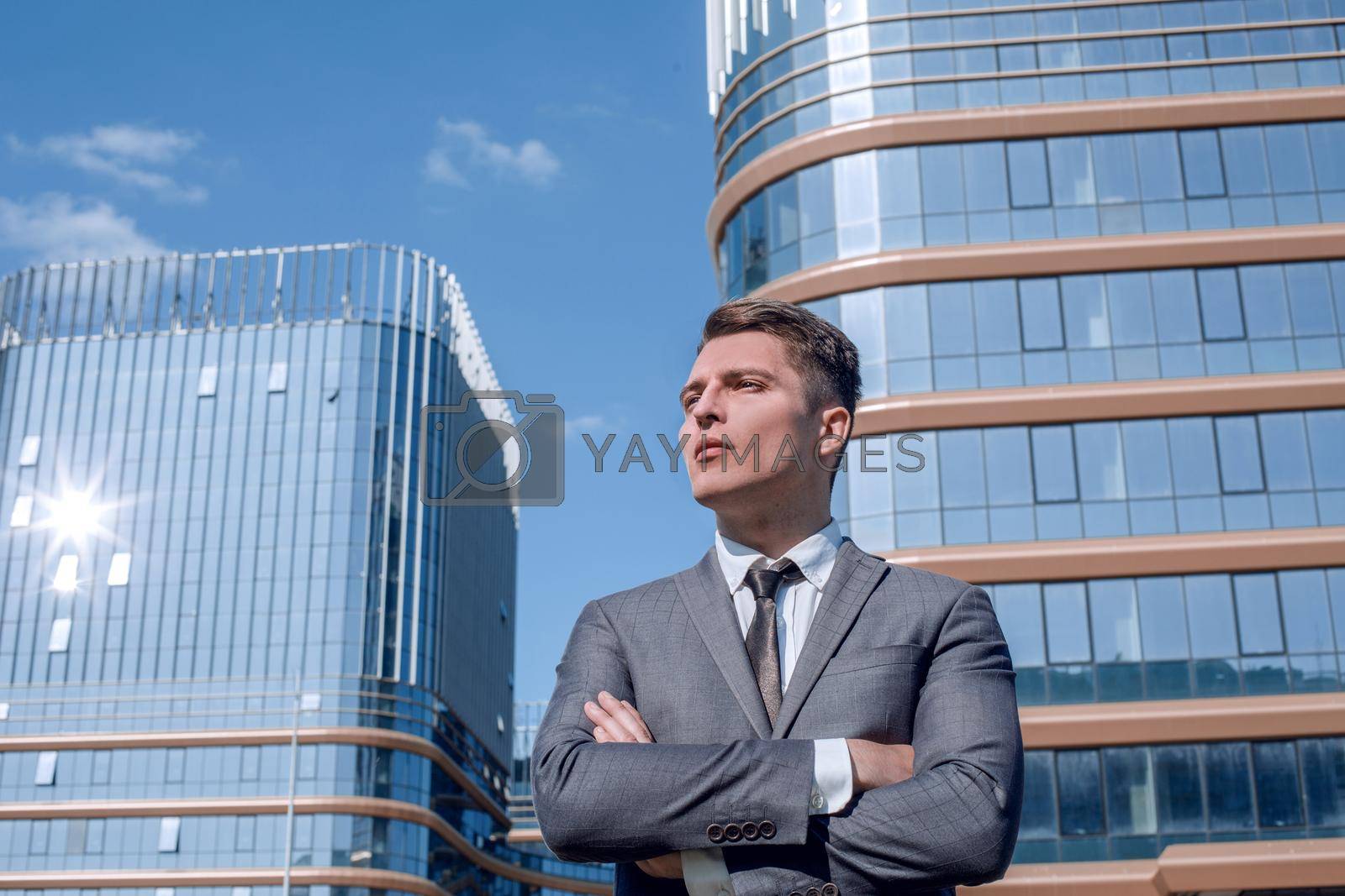 Royalty free image of serious business man standing near a tall office building. by asdf
