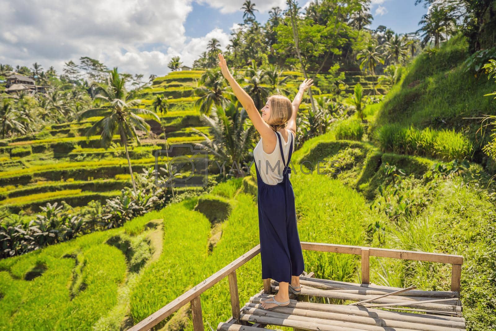 Royalty free image of Beautiful young woman walk at typical Asian hillside with rice farming, mountain shape green cascade rice field terraces paddies. Ubud, Bali, Indonesia. Bali travel concept by galitskaya