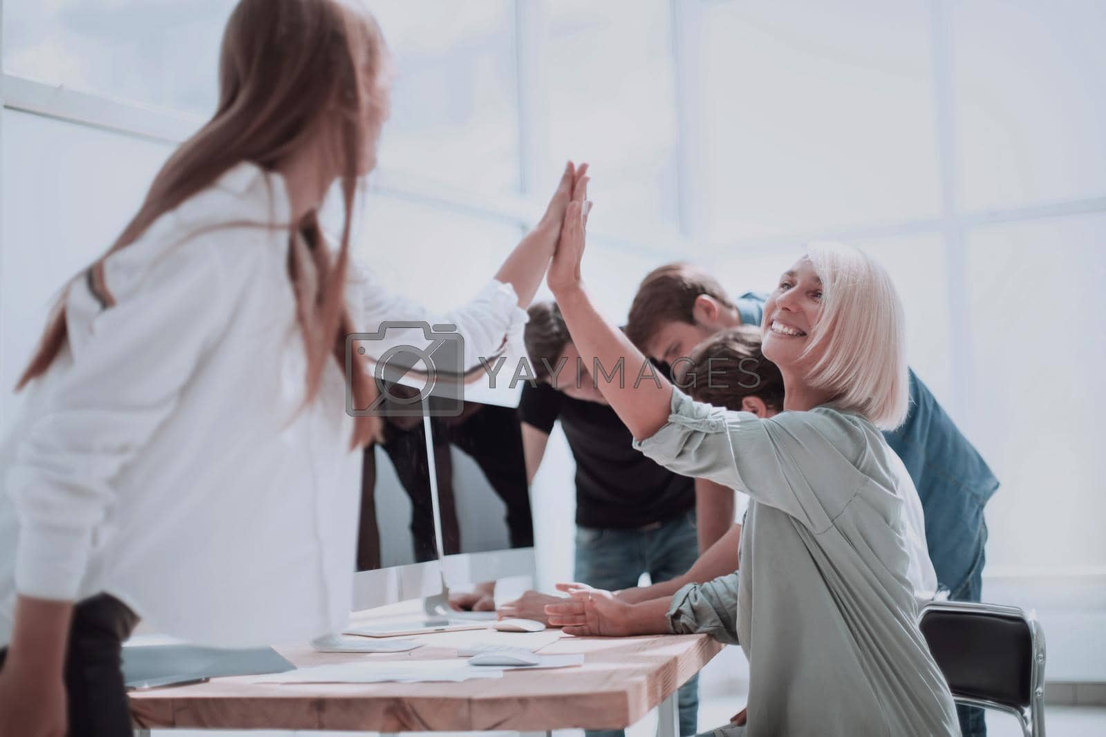 Royalty free image of smiling employees giving each other a high five by asdf