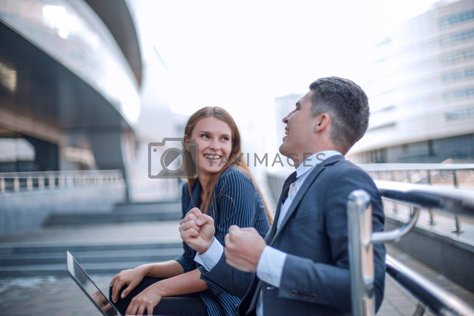 Royalty free image of happy young couple sitting in front of open laptop on city street by asdf