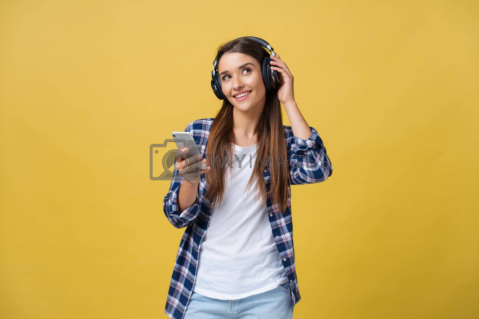 Royalty free image of Beautiful young woman in headphones listening to music and singing on yellow background by Benzoix