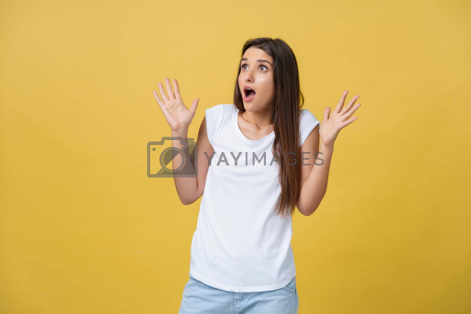Royalty free image of Beautiful female half-length portrait isolated on yellow studio backgroud. The young emotional smiling and surprised woman standing and looking at camera.The human emotions, facial expression concept by Benzoix