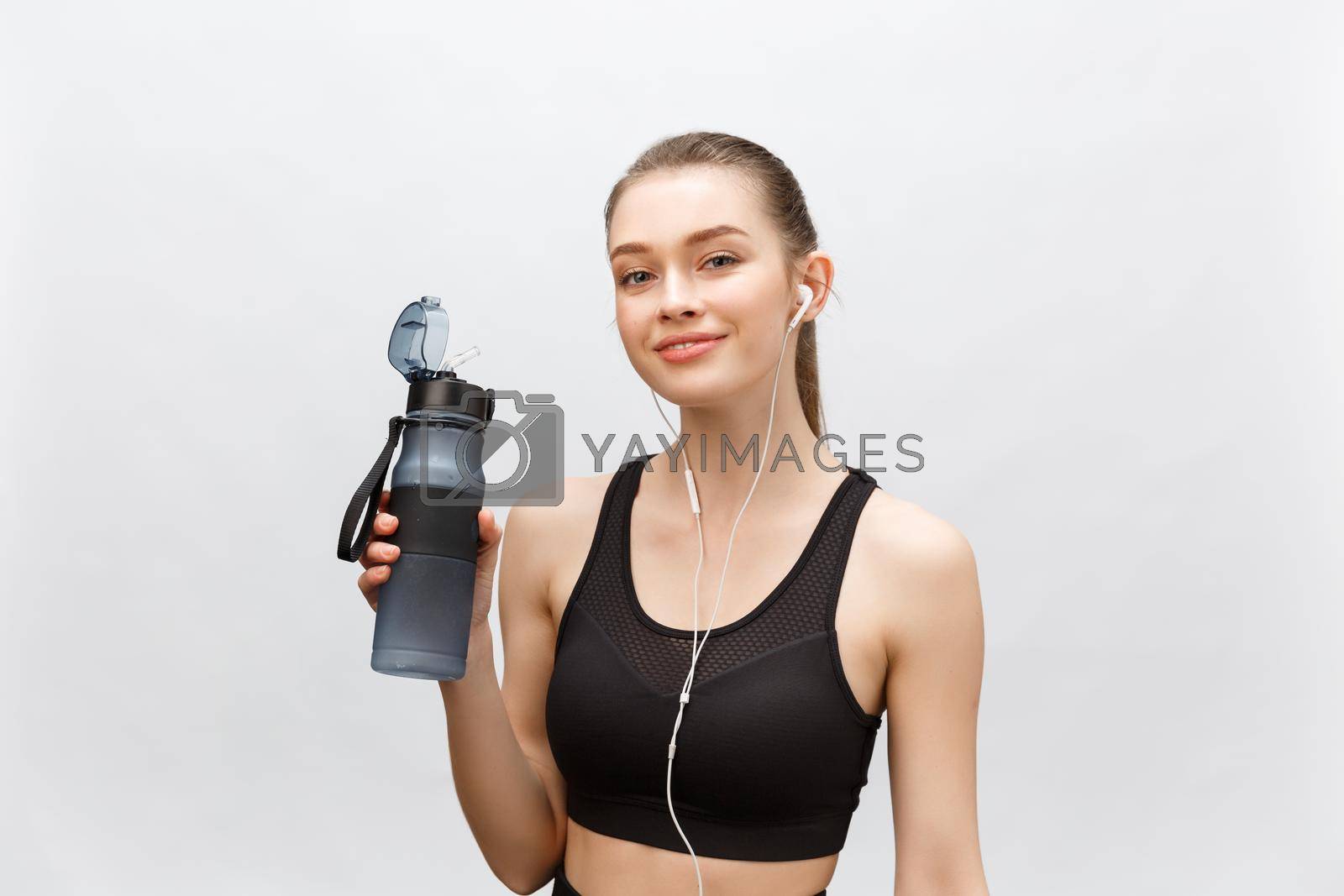 Royalty free image of Attractive relaxed young woman with drinking water and listening to music over white background. by Benzoix